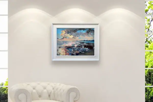 A medium shot of the sunset seascape oil painting by Agostino Veroni, featuring a white modern wood frame, displayed in a bright modern home decor or office setting with a white armchair and natural light from a window.