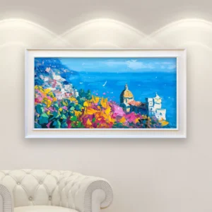 Panoramic Positano oil painting on canvas displayed in a white frame above a sofa, showing the Italian coastal village with church, colorful flowers, and blue sea in a modern impressionist Italian coastal landscape oil painting style.