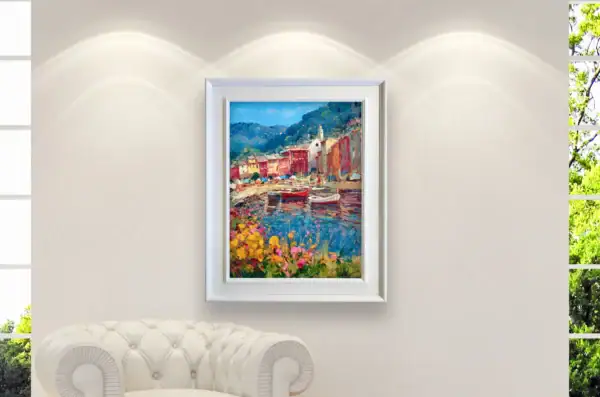 A medium shot of the Portofino harbor oil painting by Agostino Veroni, framed with a white modern wood frame in white, displayed in a bright modern office decor or living-room setting.