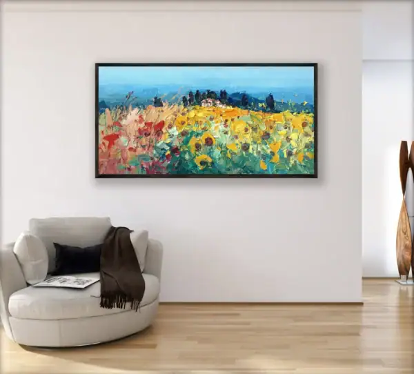 A large horizontal impressionist Tuscan sunflower field landscape painting hanging on a white wall in a modern living room next to a light circular armchair.