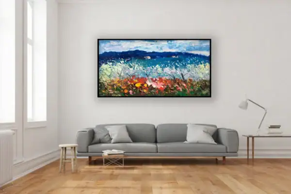 The large horizontal spring countryside canvas hanging beautifully on a minimalist wall above a contemporary grey sofa.