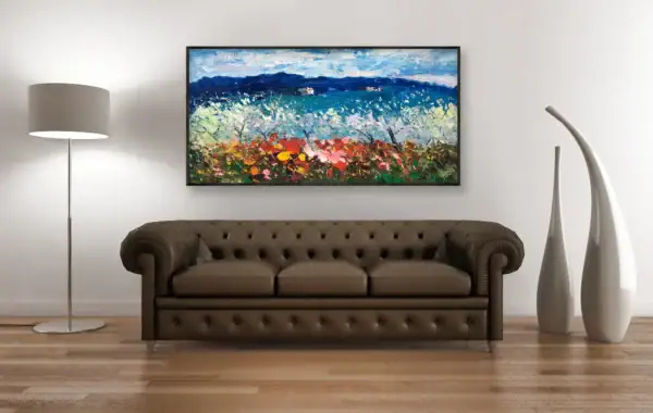 A frontal view of the colorful Tuscan field painting styled above a dark brown leather Chesterfield sofa in an elegant interior.