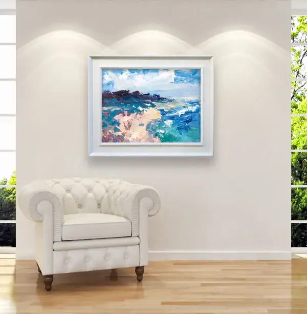 The framed horizontal Mediterranean seascape painting displayed elegantly on a clean white gallery wall above a classic white leather tufted armchair.