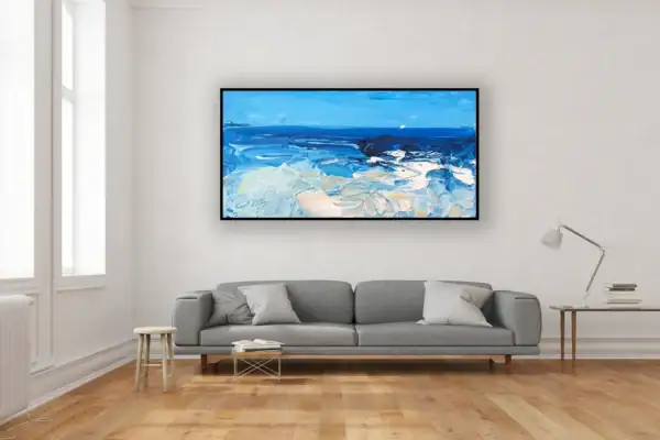 A large horizontal ocean oil painting hanging on a white wall in a bright modern living room with a grey sofa and wooden floor.