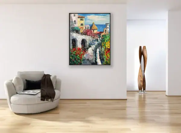 The vertical Positano coastline landscape canvas displayed in a black frame on a modern white wall in an elegant contemporary lounge room with a wooden floor.