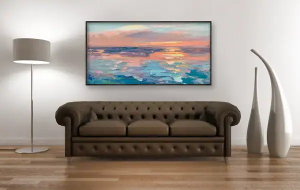 A perspective view of the horizontal pastel marine sunset oil painting hanging above a dark brown leather sofa next to modern ceramic vases.