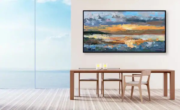 The large horizontal dramatic ocean sunset canvas displayed on a clean white wall above a contemporary rounded armchair.