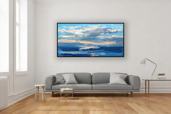 Modern impressionist sunset canvas displayed above a long grey sofa in a bright contemporary living room with wooden flooring.