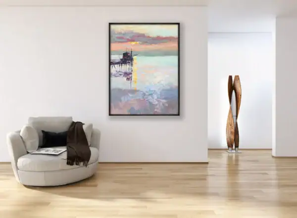 The vertical sunset seascape canvas beautifully styled inside a dark frame on a spacious white wall in a luxury contemporary lounge room next to a designer armchair.