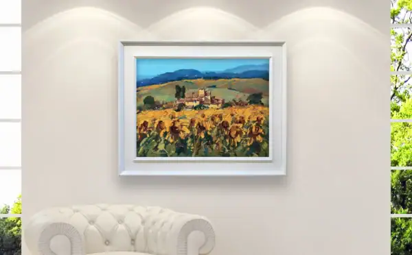 The horizontal Tuscany landscape painting beautifully styled inside an elegant white frame above a luxury white leather sofa.