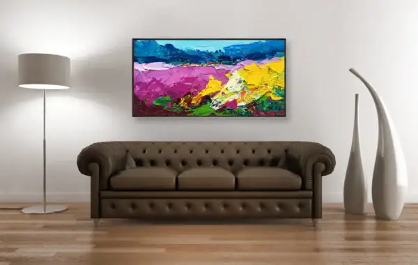 The original oil painting on a gallery wall above a classic brown leather sofa, highlighted by professional lighting.