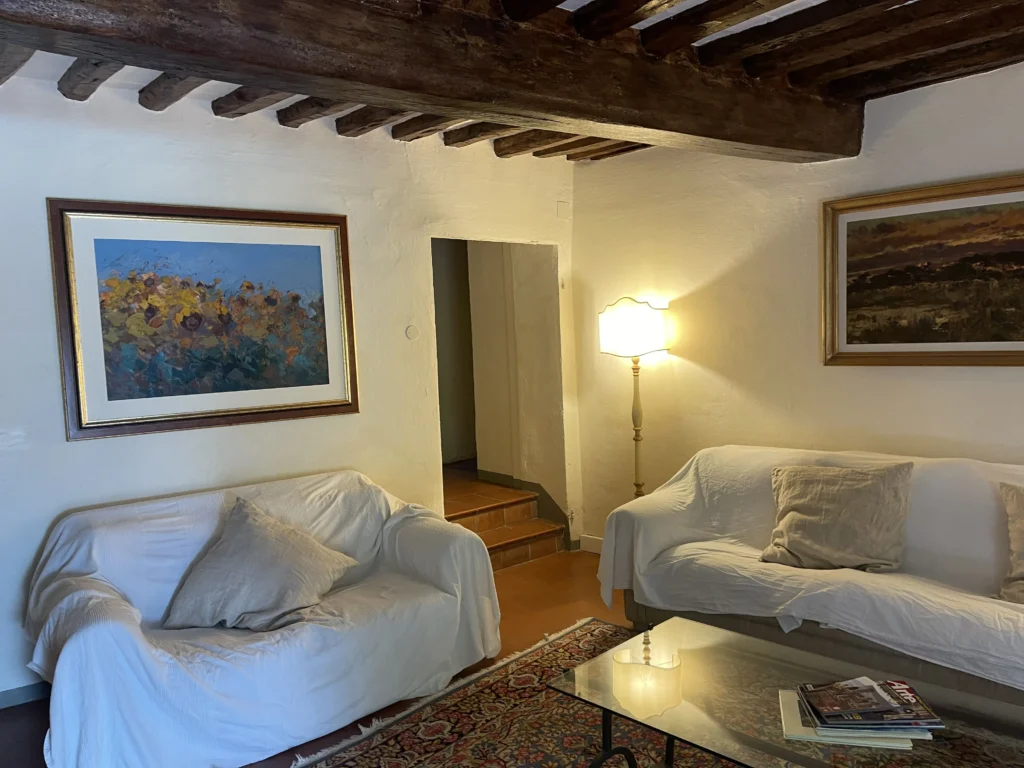 Authentic living room at Villa Minghetti Tuscan holiday rental featuring original fine art oil paintings by Agostino Veroni and traditional wooden beam ceilings.