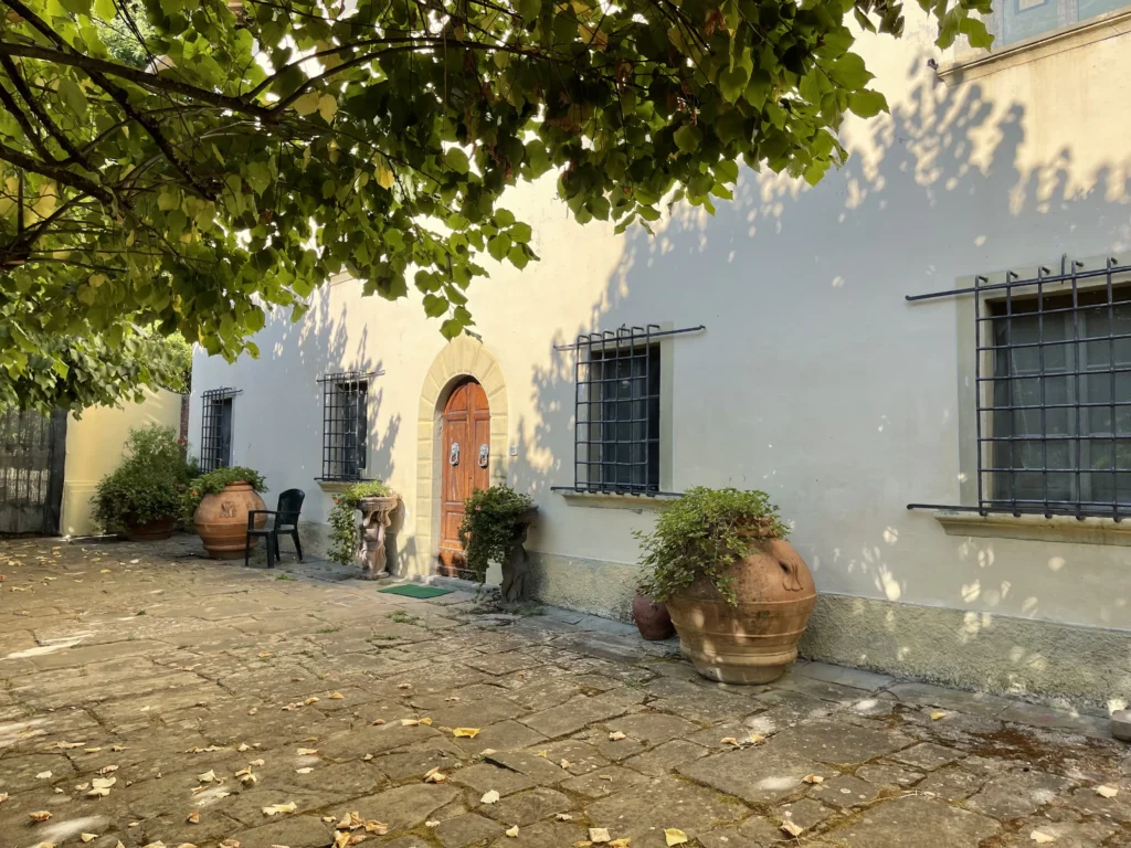 Stone-paved garden patio and traditional facade with large terracotta potted plants at Villa Minghetti Tuscan villa vacation rental.