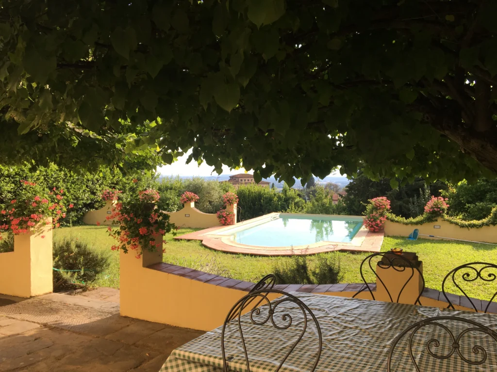 Panoramic garden terrace at Villa Minghetti, a Tuscan villa vacation rental with outdoor seating, flowers, and private swimming pool view.