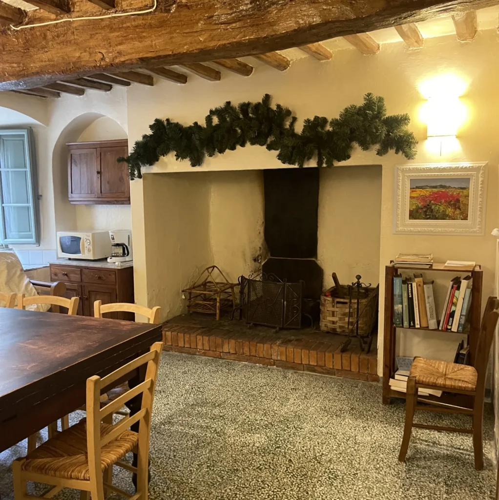 Traditional Tuscan kitchen with stone fireplace, wooden beams, and dining area at Villa Minghetti, perfect for authentic cooking.