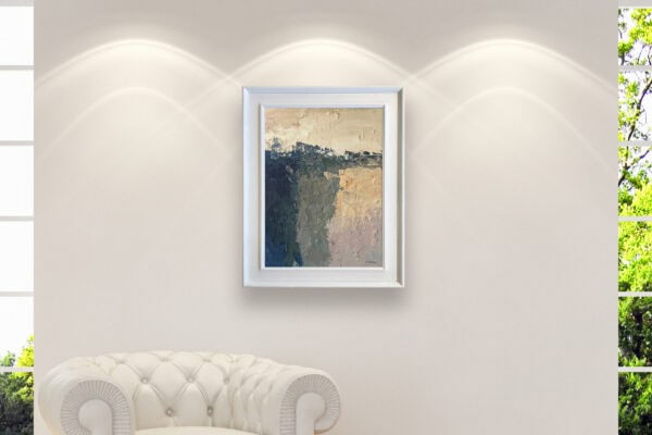 A modern abstract landscape oil painting displayed in a white frame on a living room wall above a classic white armchair.