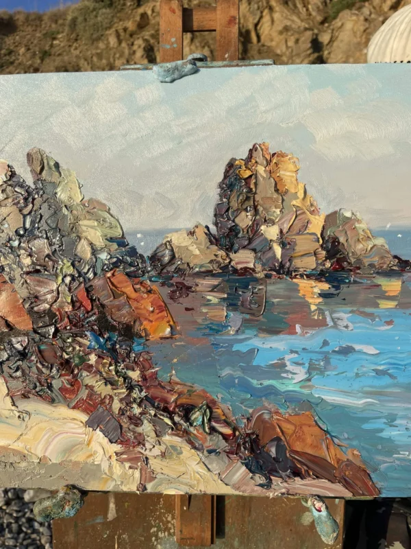 A modern impressionist sea cliffs oil painting on a wooden easel showing heavy impasto and palette knife textures in natural light.