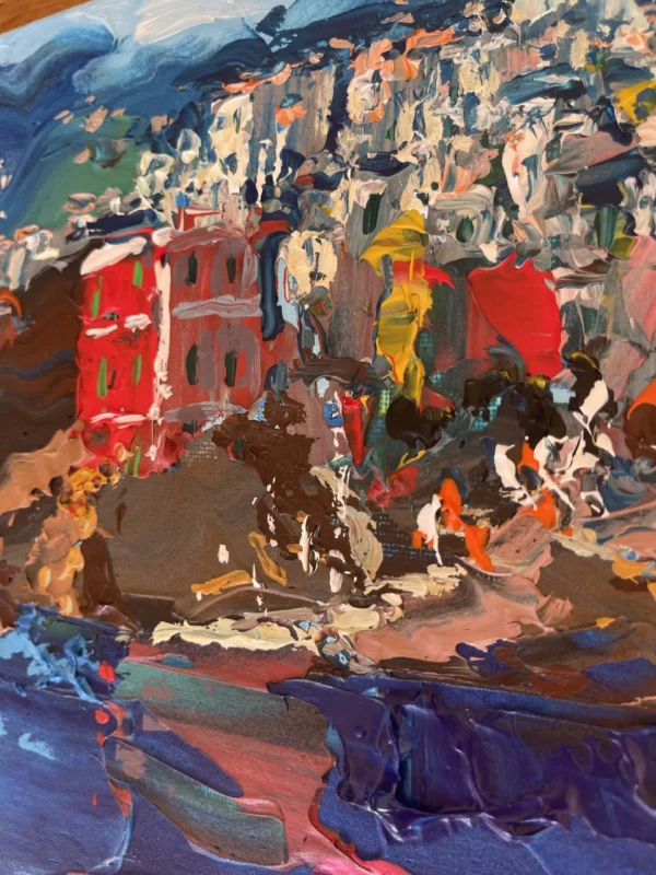 Close-up macro view of red colorful cliffside houses painted with expressive palette knife strokes on canvas.