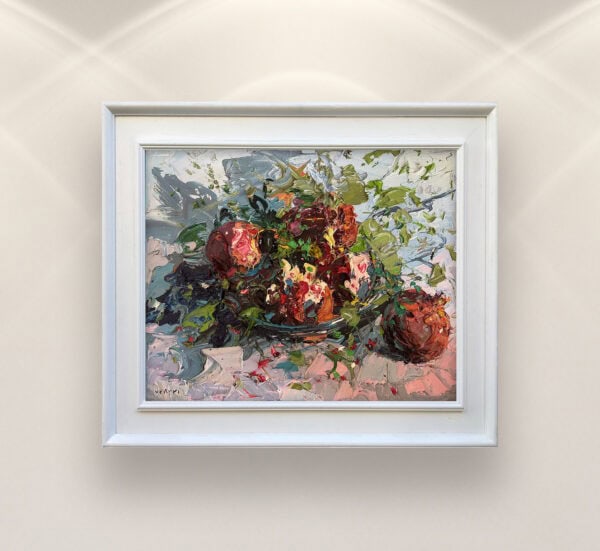 Pomegranate oil painting on canvas by Agostino Veroni, framed in white. Close-up texture of deep crimson fruit and green leaves with heavy impasto finish on a modern wall.