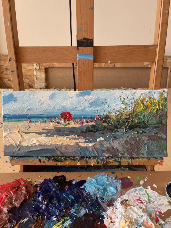 Summer beach oil painting on canvas by Agostino Veroni on a wooden easel. Shows thick impasto technique, an artistic palette with colors, and a panoramic coastal scene with blue sea and sand.
