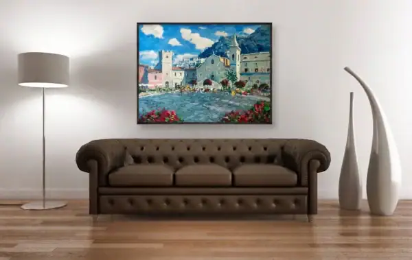 Taormina oil painting living room decor showing an impressionist canvas in a thin black frame above a brown leather Chesterfield sofa in an elegant warm minimalist room with wooden floor and floor lamp.